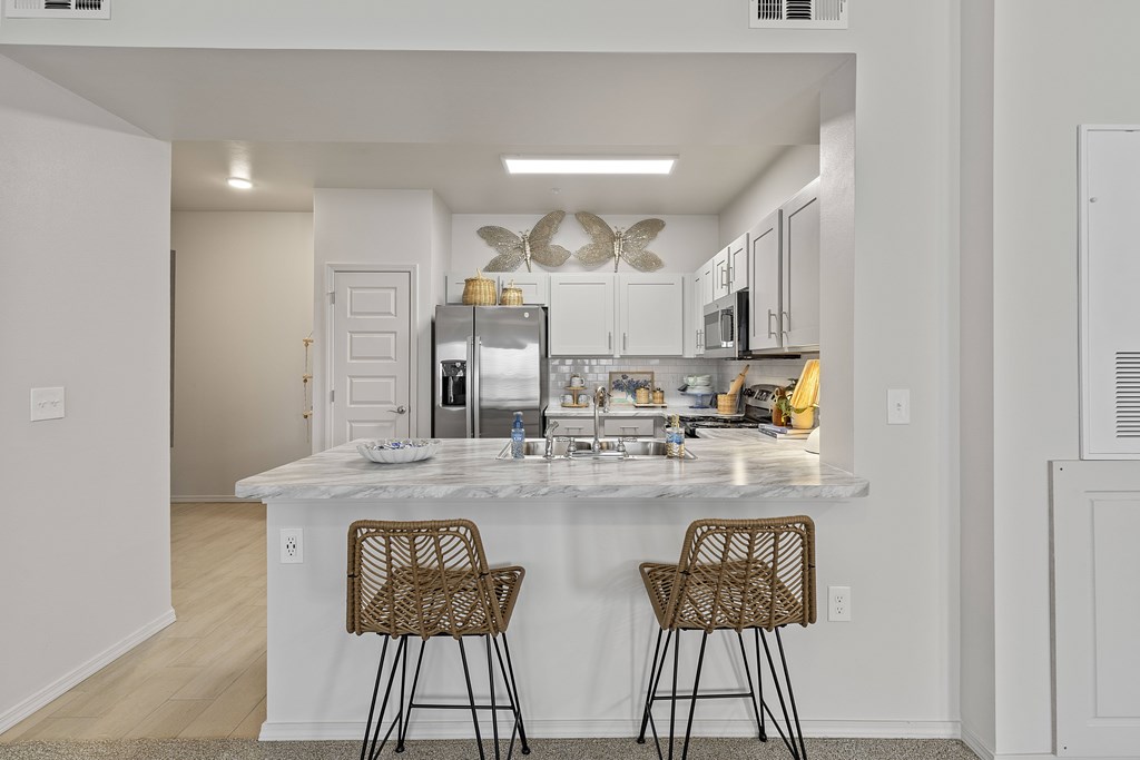 A kitchen with a marble countertop and two chairs.