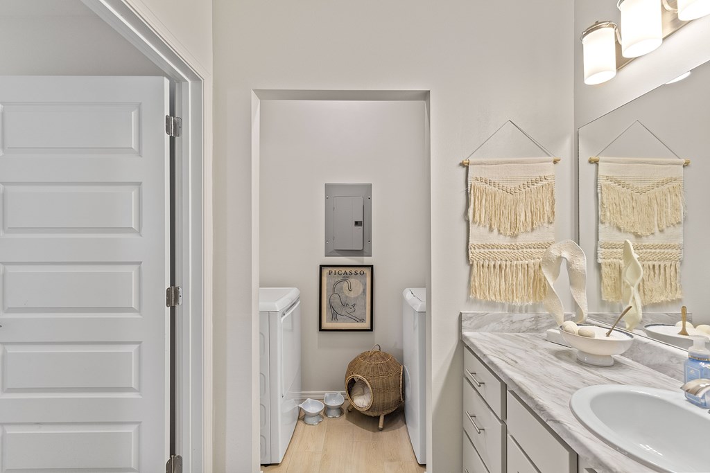 A bathroom with a white door, a white sink, and a white toilet.