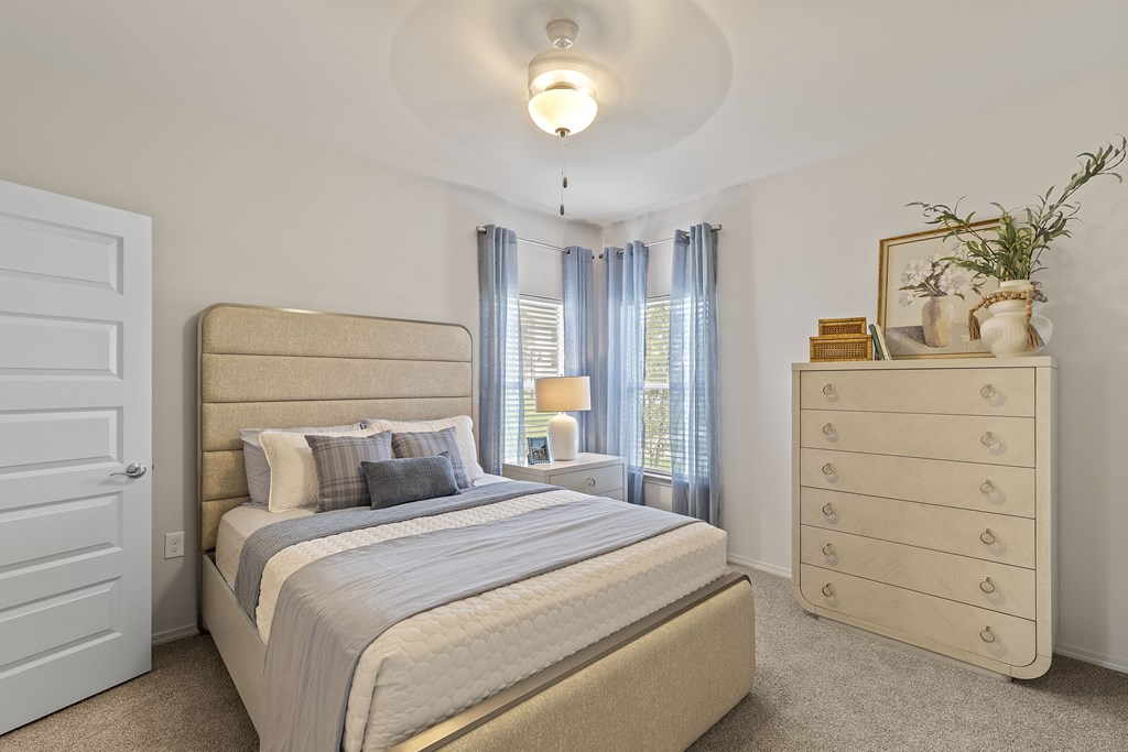 A bedroom with a large bed, a dresser, and a window with curtains.