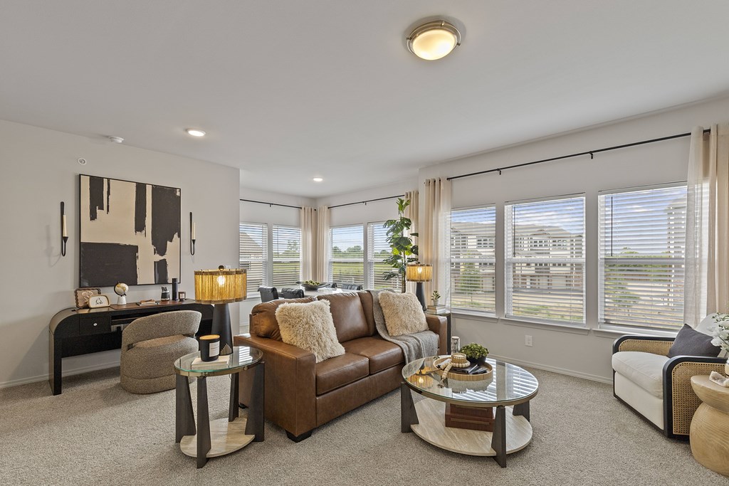 A living room with a brown leather couch, a glass coffee table, and a television.
