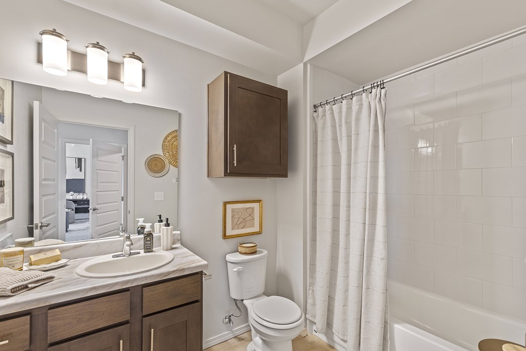 A bathroom with a white sink, toilet, and shower curtain.