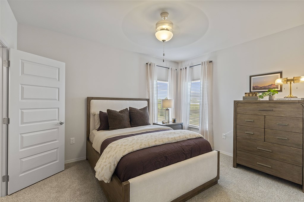 A bedroom with a large bed, a dresser, and a window with curtains.