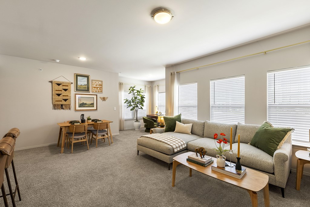 A living room with a grey couch, a wooden coffee table, and a dining table with chairs.