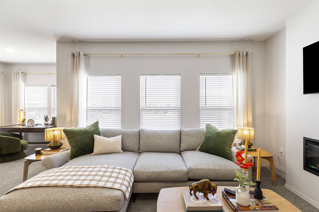 A living room with a grey sofa and a coffee table with a vase of flowers on it.