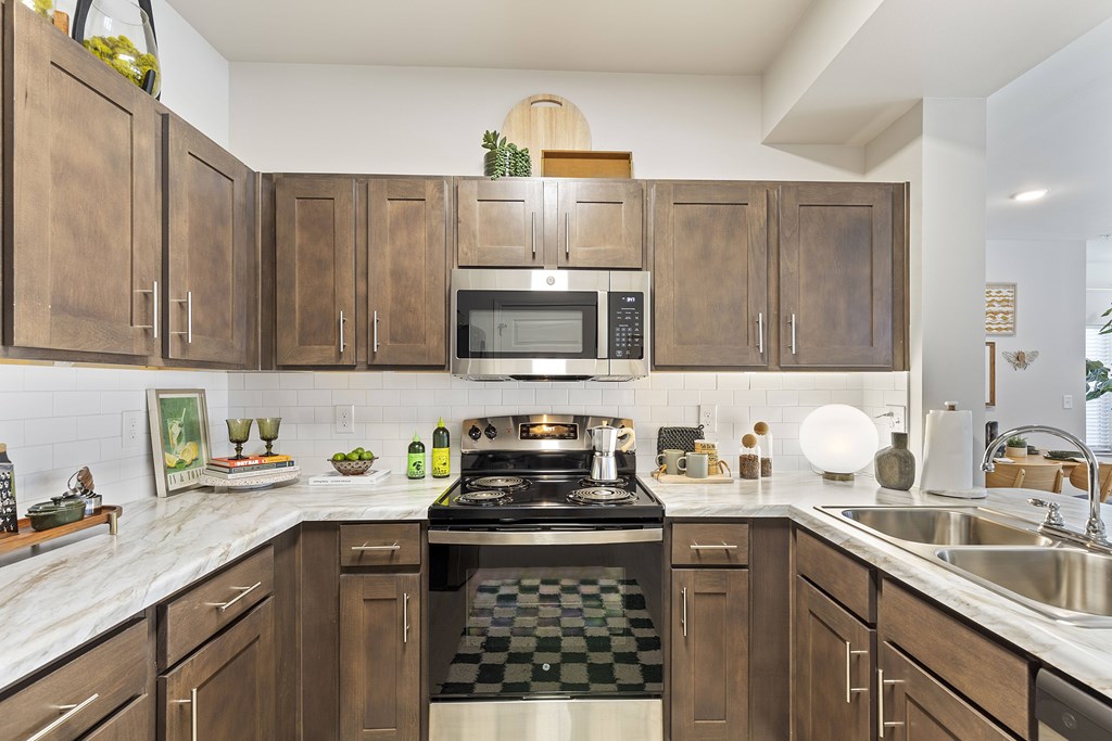 A kitchen with brown cabinets and a black and white checkered floor.