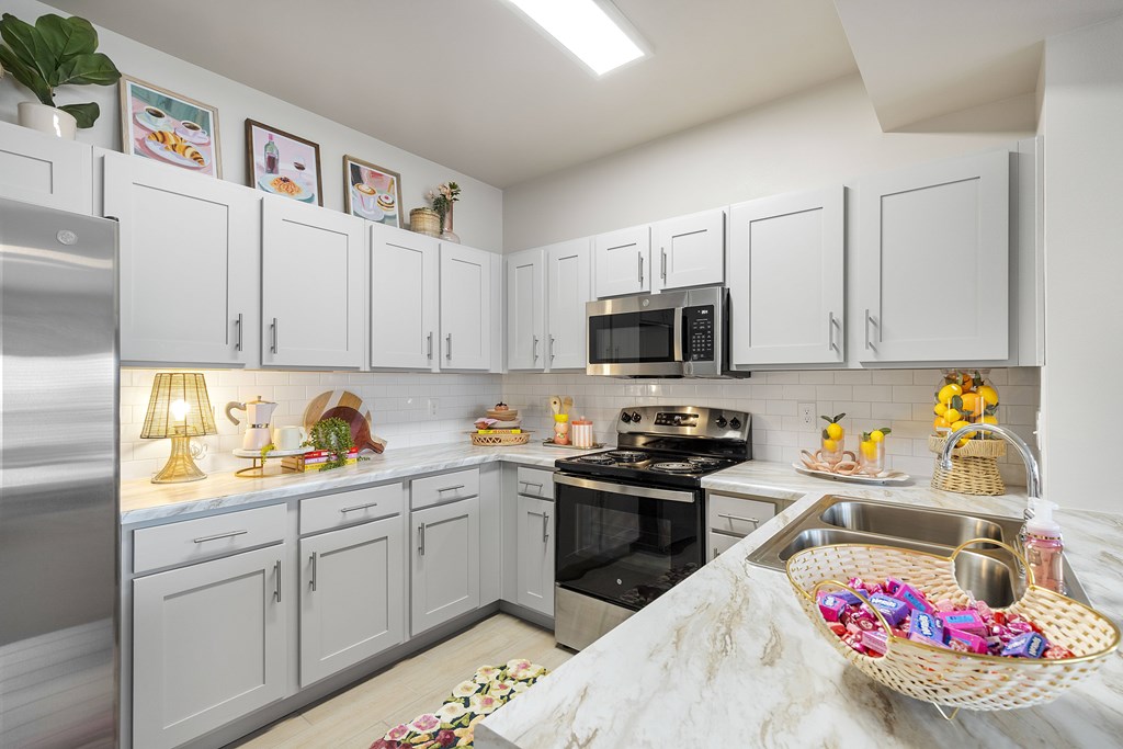 A kitchen with white cabinets and a stainless steel refrigerator.