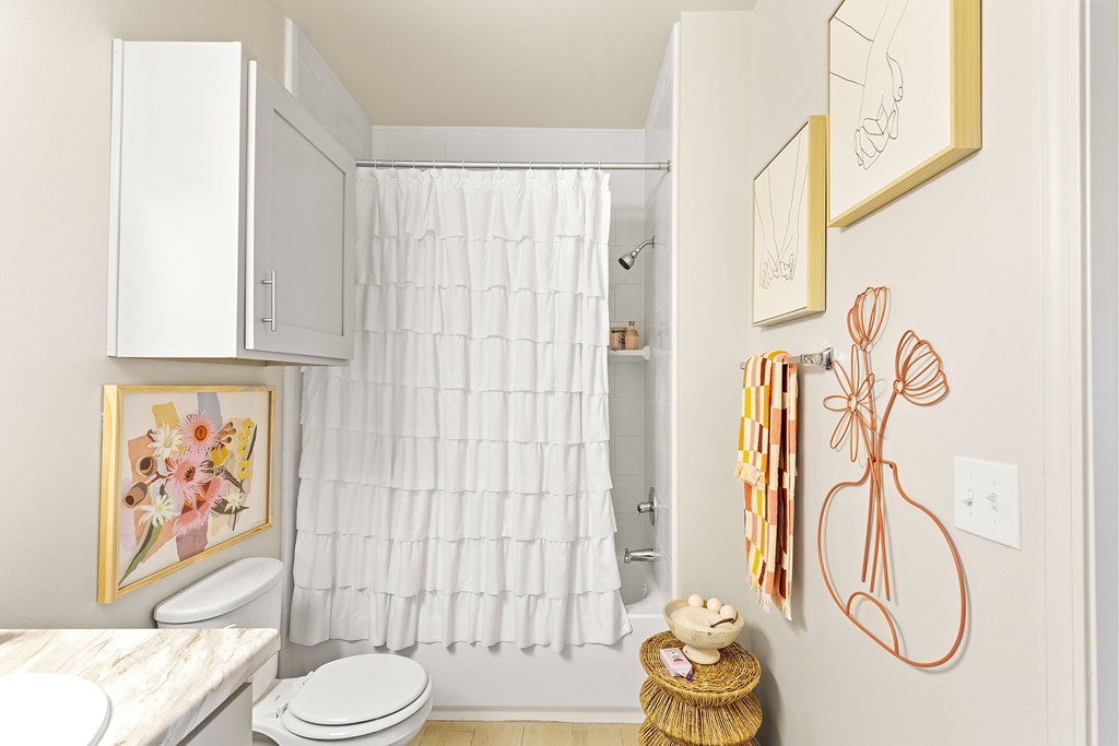 A bathroom with a toilet, a shower curtain, and a teddy bear.