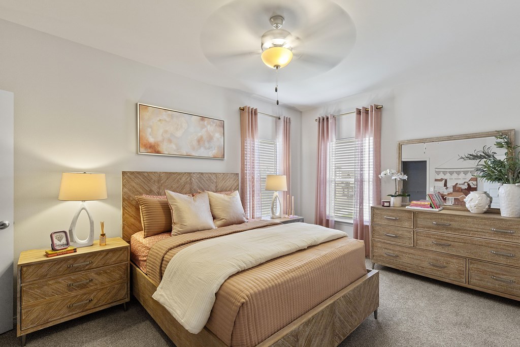 A bedroom with a large bed, a dresser, and a ceiling fan.