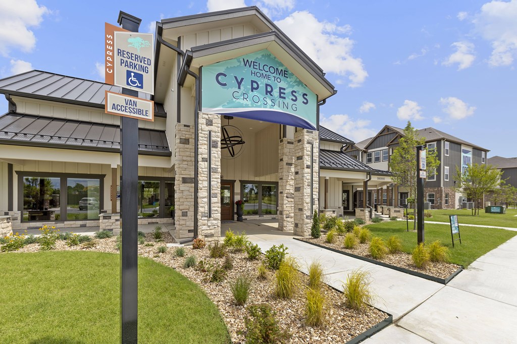 A building with a sign that says "Welcome to Cypress Crossing" in front of it.