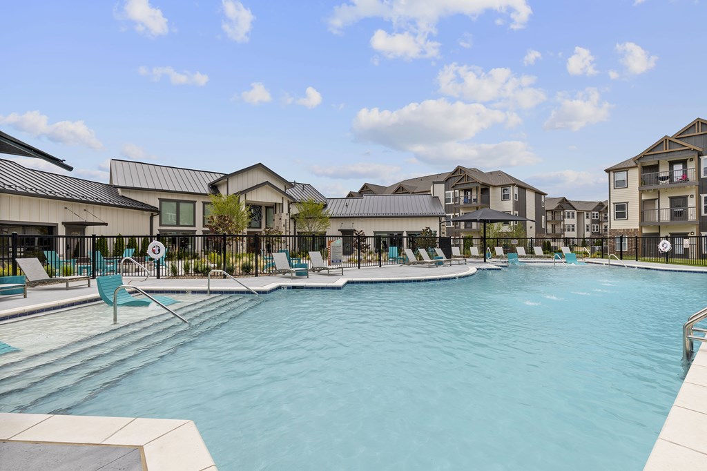 A large swimming pool in front of a building with a fence around it.