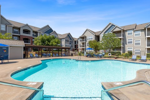 A large swimming pool in front of apartment buildings.