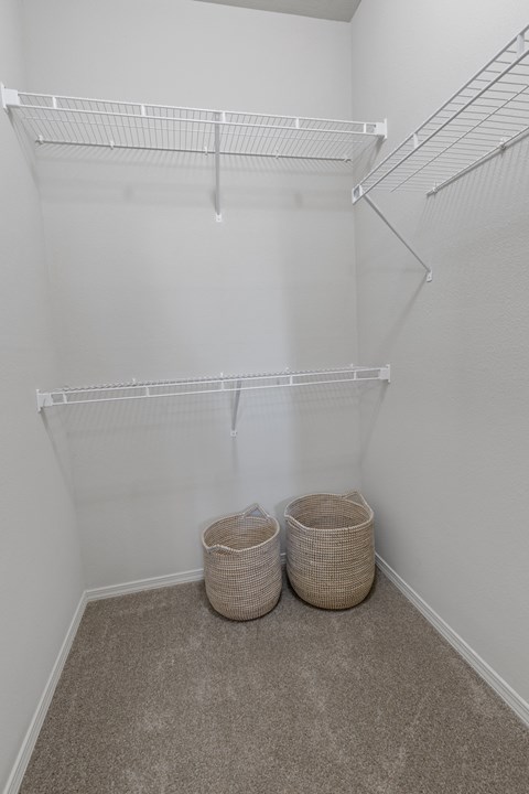 A white closet with two baskets on the floor.