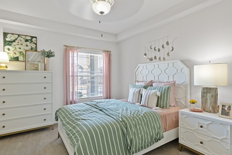 A bedroom with a bed, nightstand, and dresser.