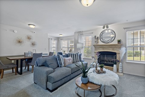 A living room with a grey couch and a fireplace.