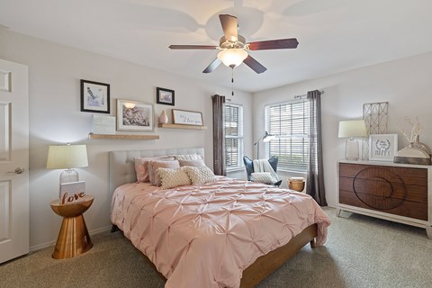 A bedroom with a bed, a dresser, and a ceiling fan.