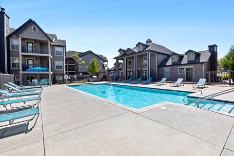 A swimming pool surrounded by lounge chairs and buildings.