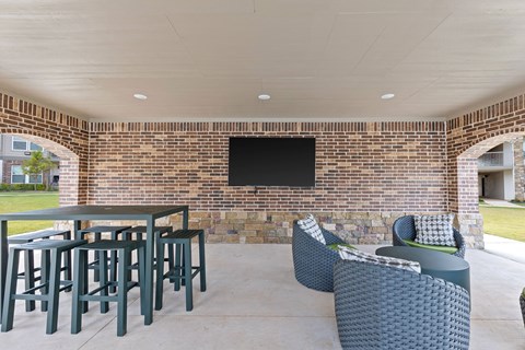 A patio with a brick wall and a television mounted on it.