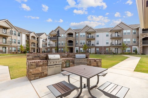 A picnic table and bench are in front of apartment buildings.