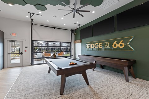 A pool table in a room with a green wall and a sign that says "RIDGE AT 66".