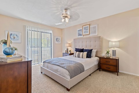 A bedroom with a large bed, a nightstand, and a dresser.