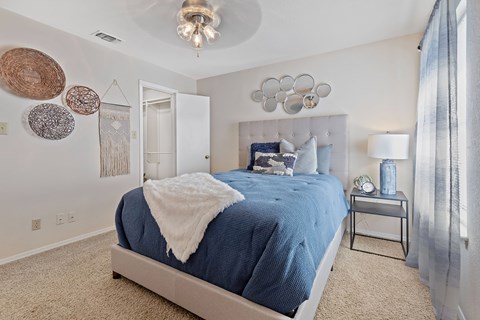 A bedroom with a blue bedspread and a white blanket.