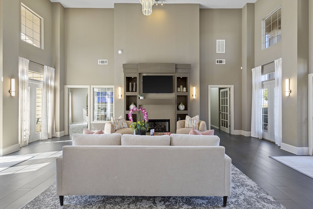 A large, modern living room with a grey sofa and a fireplace.