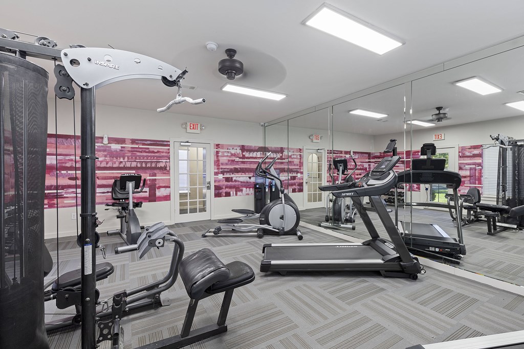 A gym with a variety of equipment including treadmills, weights, and exercise machines.
