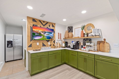A kitchen with green cabinets and a wooden framed picture on the wall.
