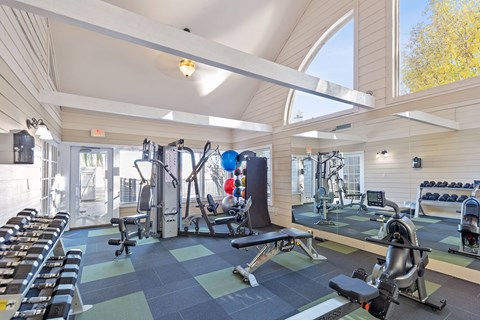 A gym with a variety of equipment including treadmills, weights, and exercise machines.