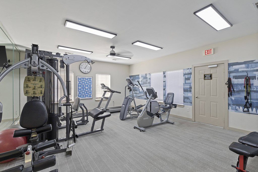 A gym with a variety of equipment including a weight machine, a bench press, and a treadmill.