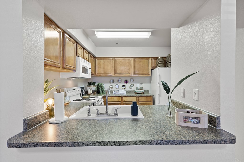 A kitchen with granite countertops and wooden cabinets.