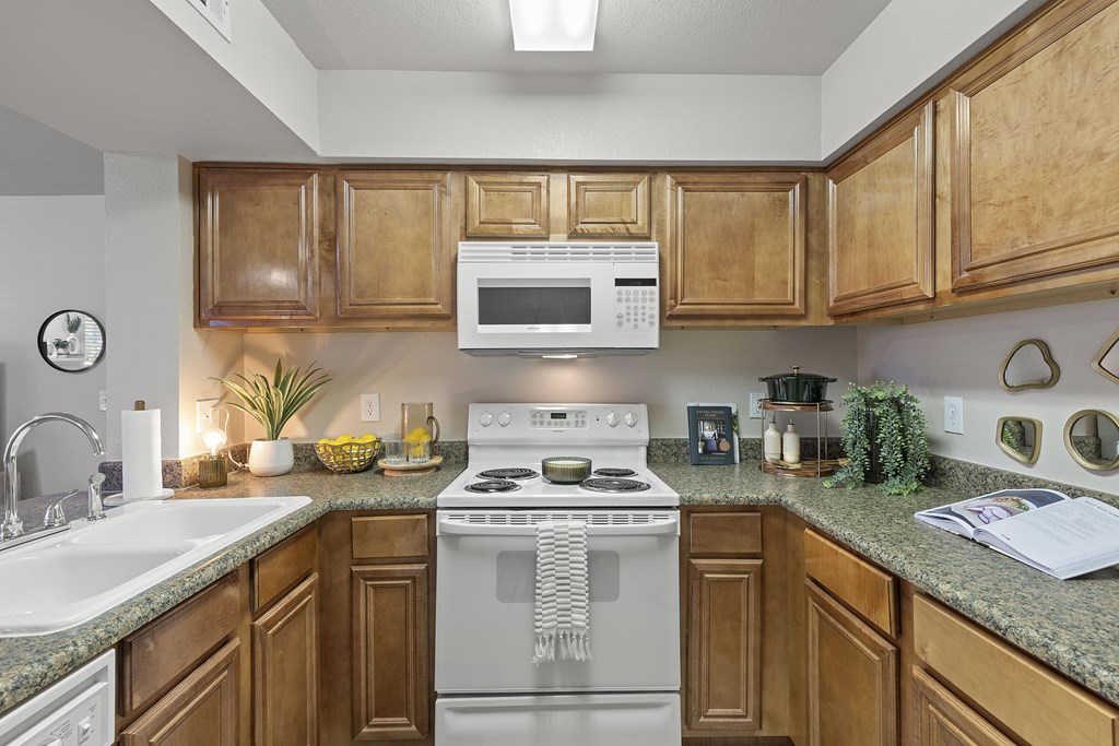 A kitchen with wooden cabinets and a white stove top oven.