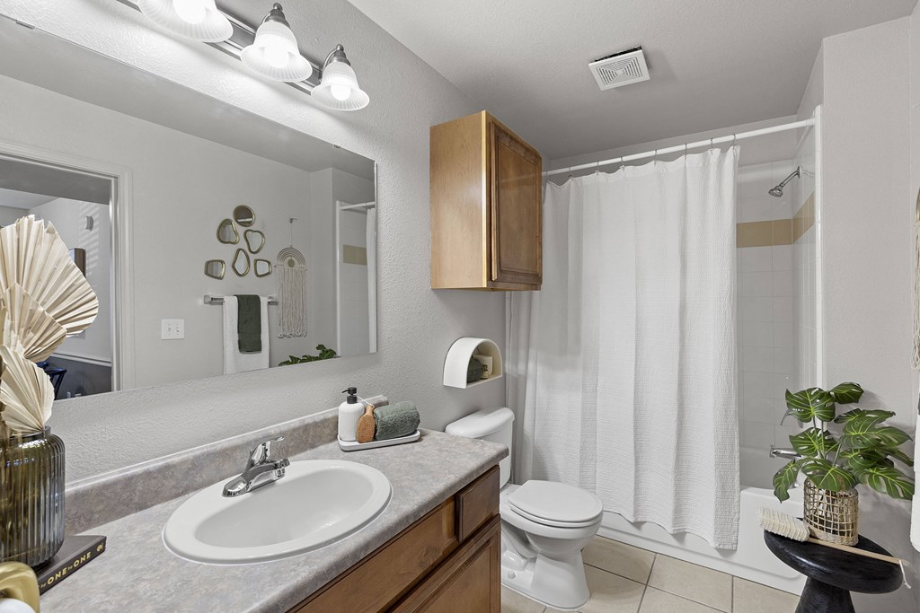 A bathroom with a white toilet, sink, and shower curtain.