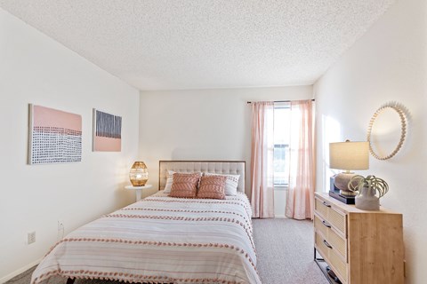 A bedroom with a large bed and a wooden dresser.