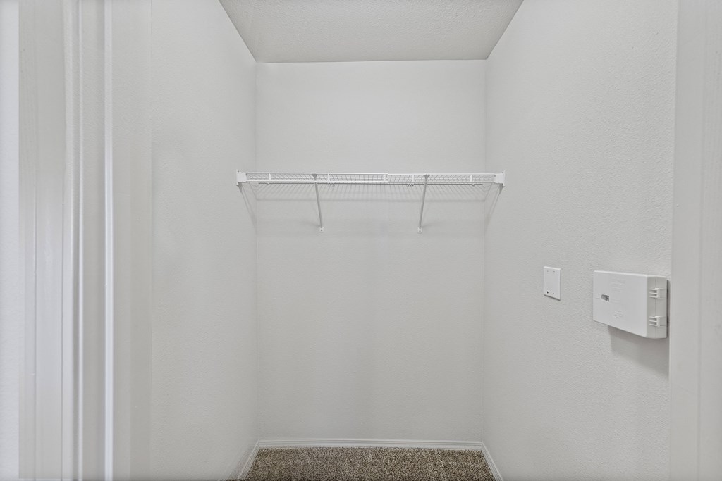 A small, empty room with a shelf and a light switch on the wall.