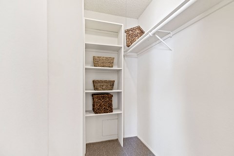A white shelving unit with baskets and boxes on it.
