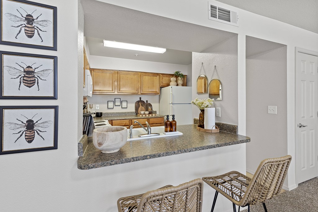 A kitchen with a sink, a chair, and three framed pictures of bees on the wall.