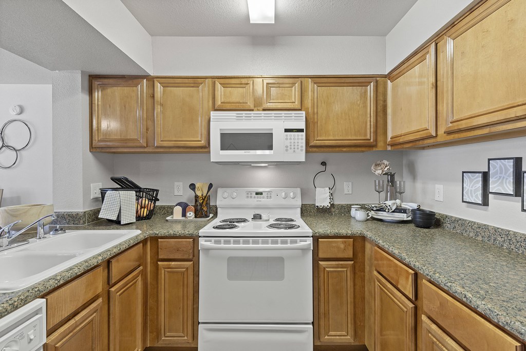 A kitchen with a white stove and wooden cabinets.