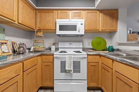 A kitchen with a white stove and wooden cabinets.