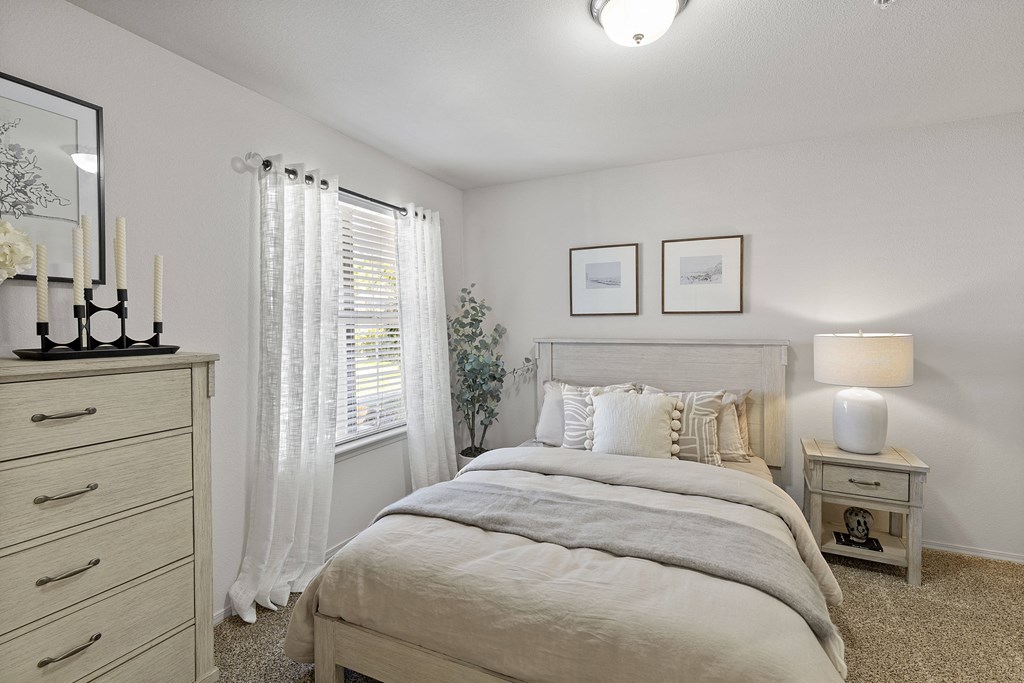 A bedroom with a large bed, a dresser, and a nightstand.
