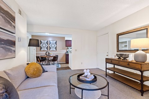 A living room with a grey couch, a coffee table, and a lamp.