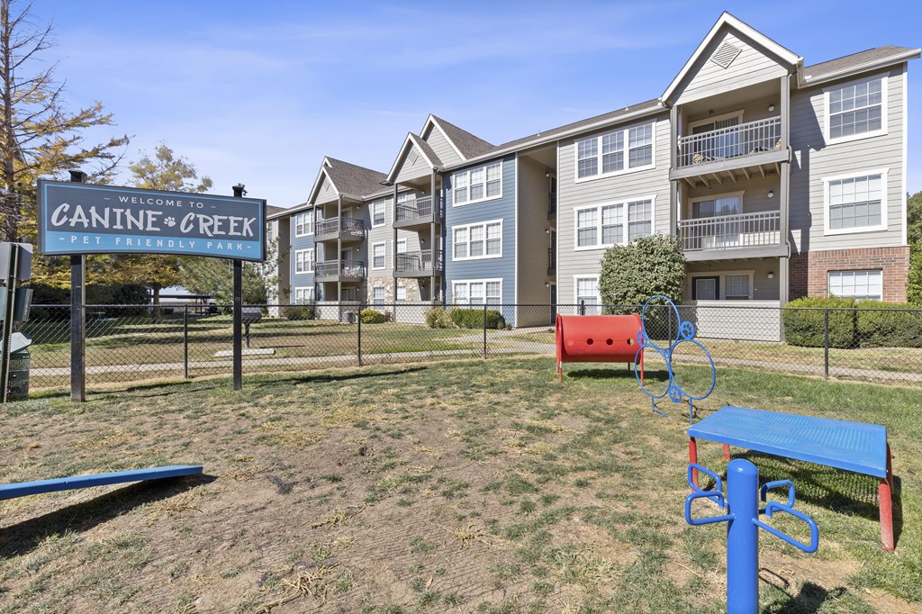 A sign that says "Canine Creek" is in front of apartment buildings.