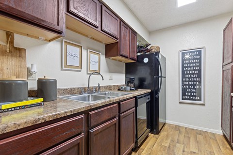 A kitchen with wooden cabinets and a black refrigerator.