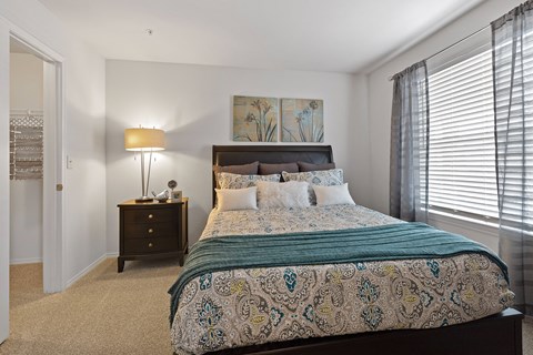 A bedroom with a large bed and a lamp on a side table.