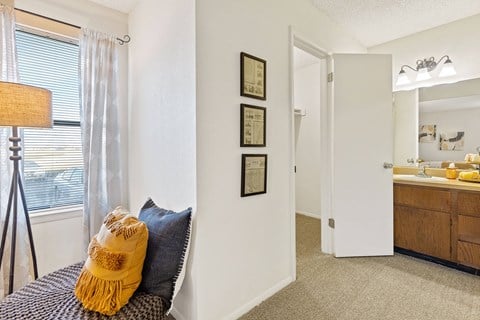 A bedroom with a bed, a window with blinds, a nightstand, a dresser, and a mirror.