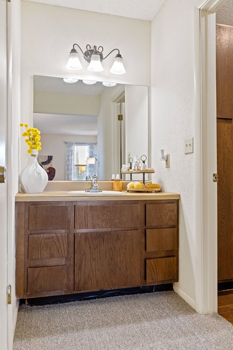 A bathroom with a wooden vanity and a mirror above it.