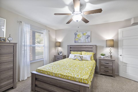 A bedroom with a bed, dresser, and ceiling fan.