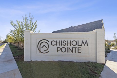 A sign that says Chisholm Pointe stands in front of a building.