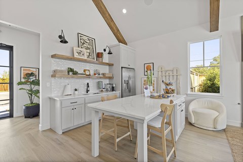 A white kitchen with wooden chairs and a table.