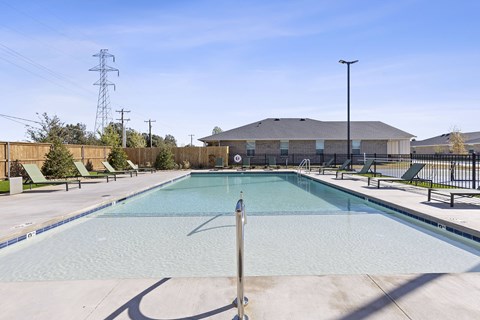 A large outdoor swimming pool with a diving board and loungers.